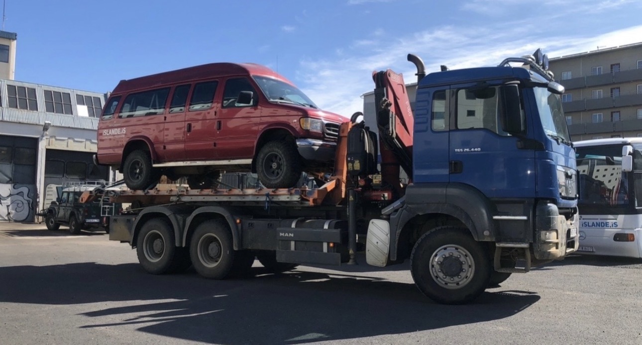MAN transport truck carrying a red minibus